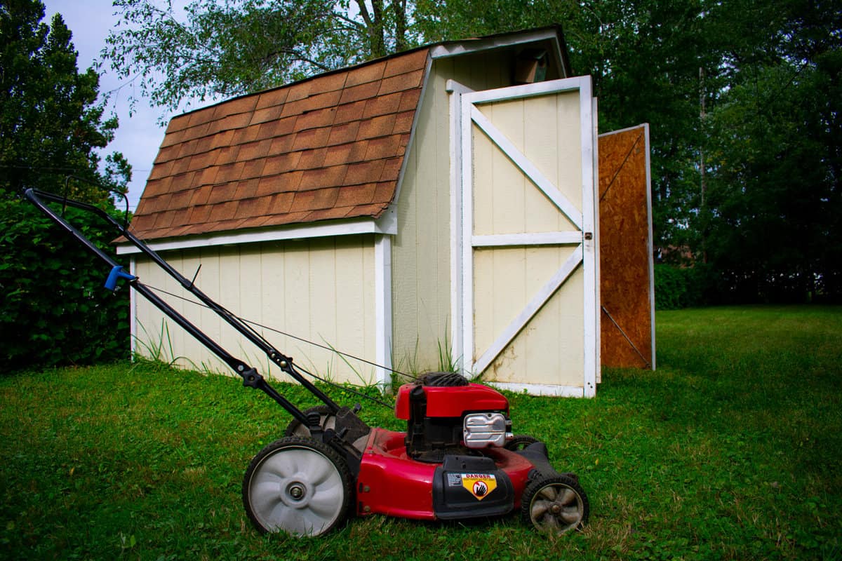 Red and Black Lawn Mower in the Spring With Shed in the Backyard