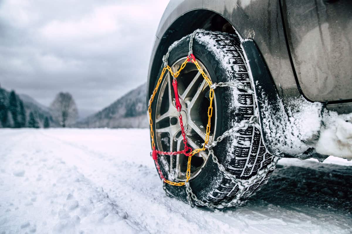 Snow chains on tire. Detail of wheel on wimter road