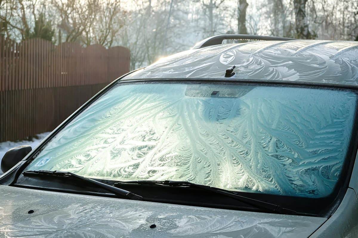 The frozen window of a car in cold winter day. Frost pattern