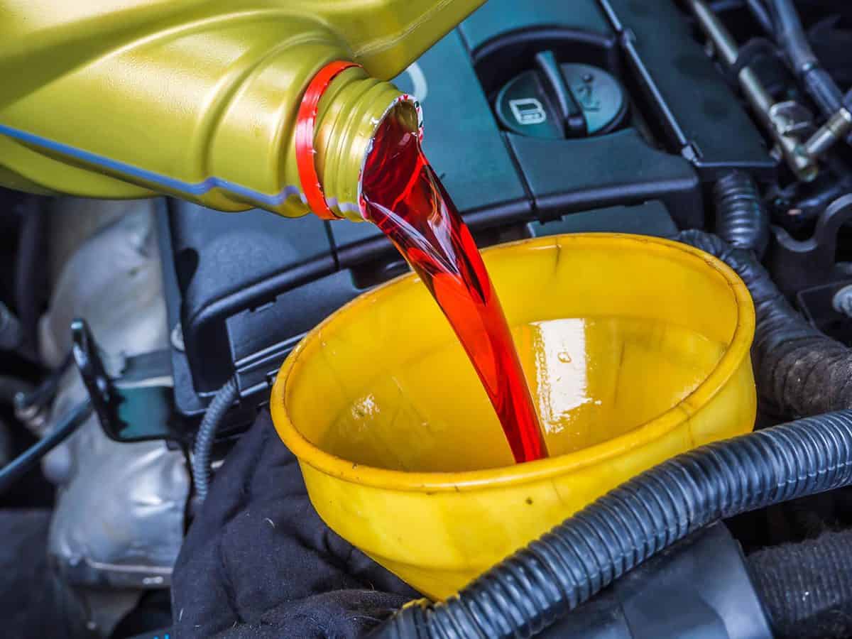 Transmission oil fill up in a car engine with yellow cone spire shape container