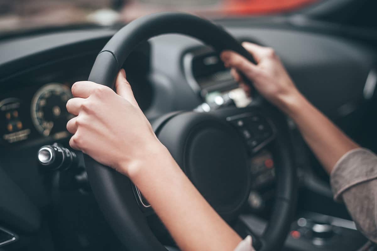 Woman holding the leather steering wheel