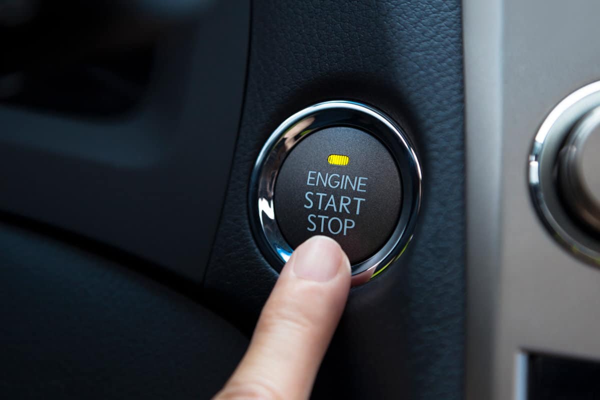 finger pressing the Engine start stop button of a car