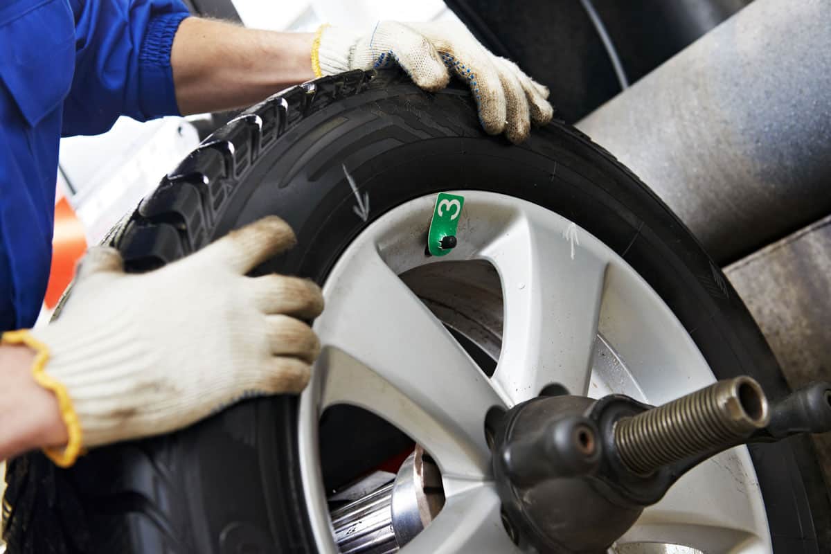 mechanic repairman hands during balancing automobile car wheel on balancer
