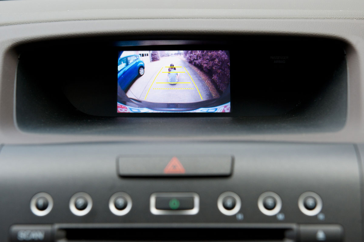 A car back up camera video diplay in the automobile dashboard showing a wide angle view of what's behind the car