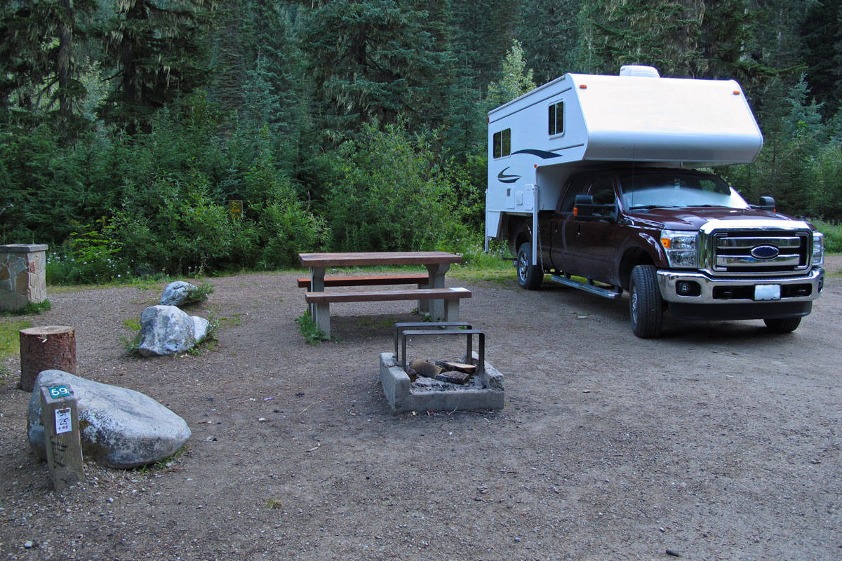 A small camping area with a truck camper parked on the back
