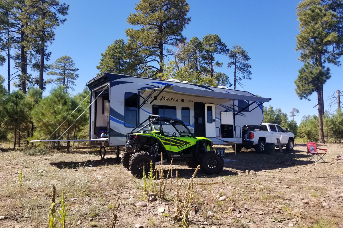 A toy hauler at camping ground with a Polaris RZR parked on the side