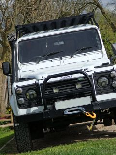 A white Land Rover Defender with a black bull bar with fog lights installed on it, How Much Does A Bull Bar Weigh?