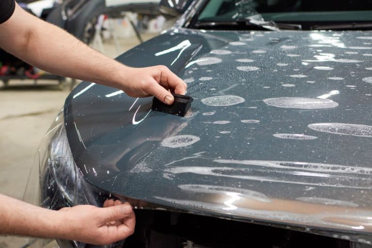 Auto detailer installing a glossy car wrap, How Much Does It Cost To Wrap A Car In Black?
