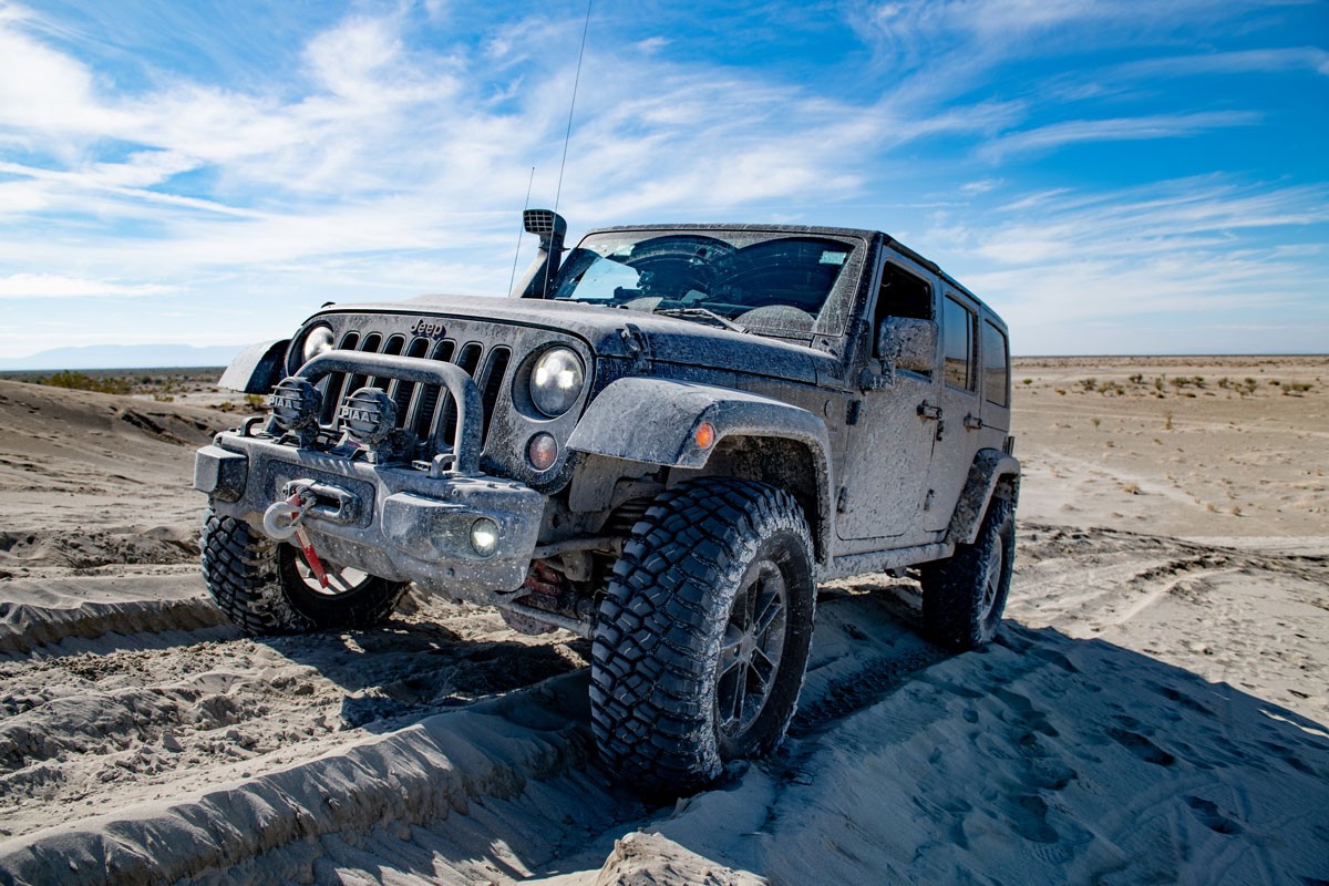 Black jeep all road in a desert landscape with a blue cloudy sky in daytime