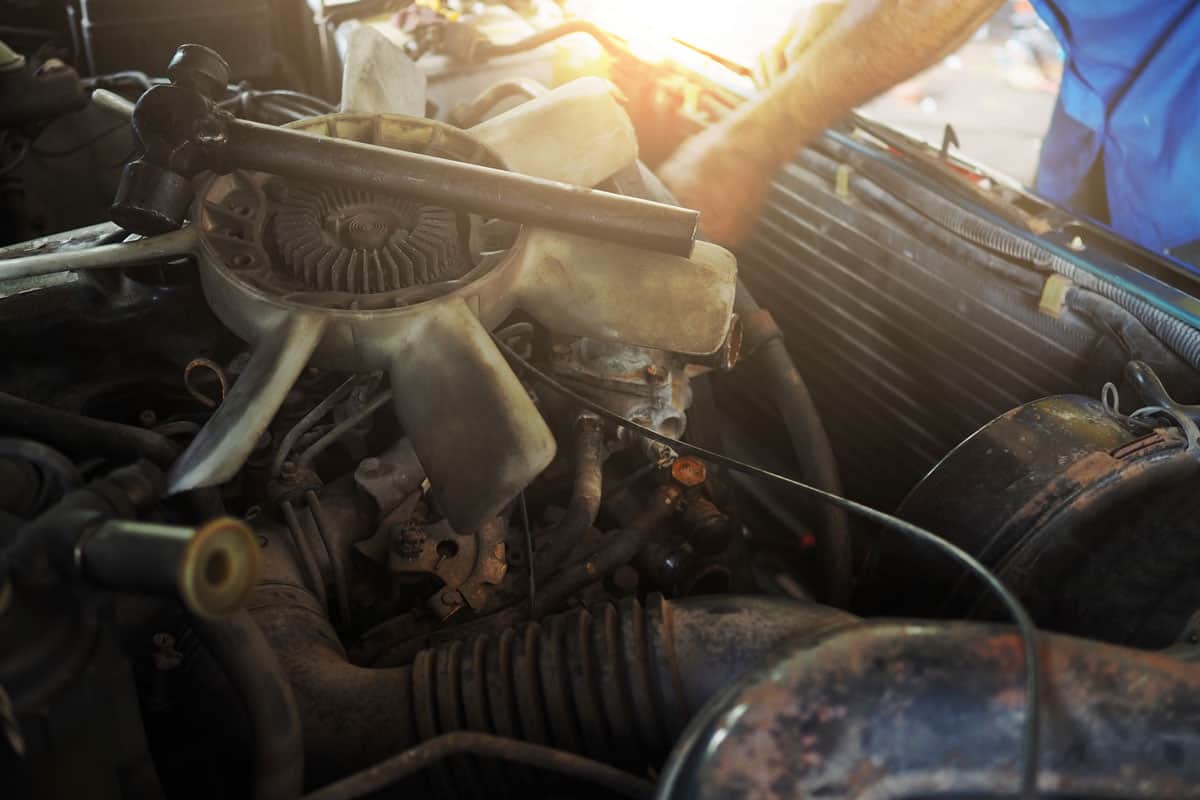 Broken cooling fan motor of car is being removed in garage in auto repair shop