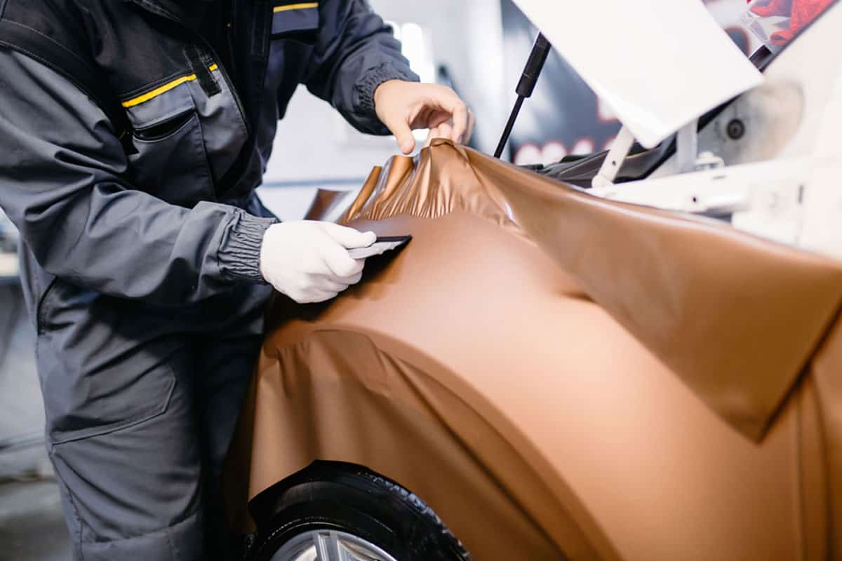 Car auto detailer applying brown car wrap