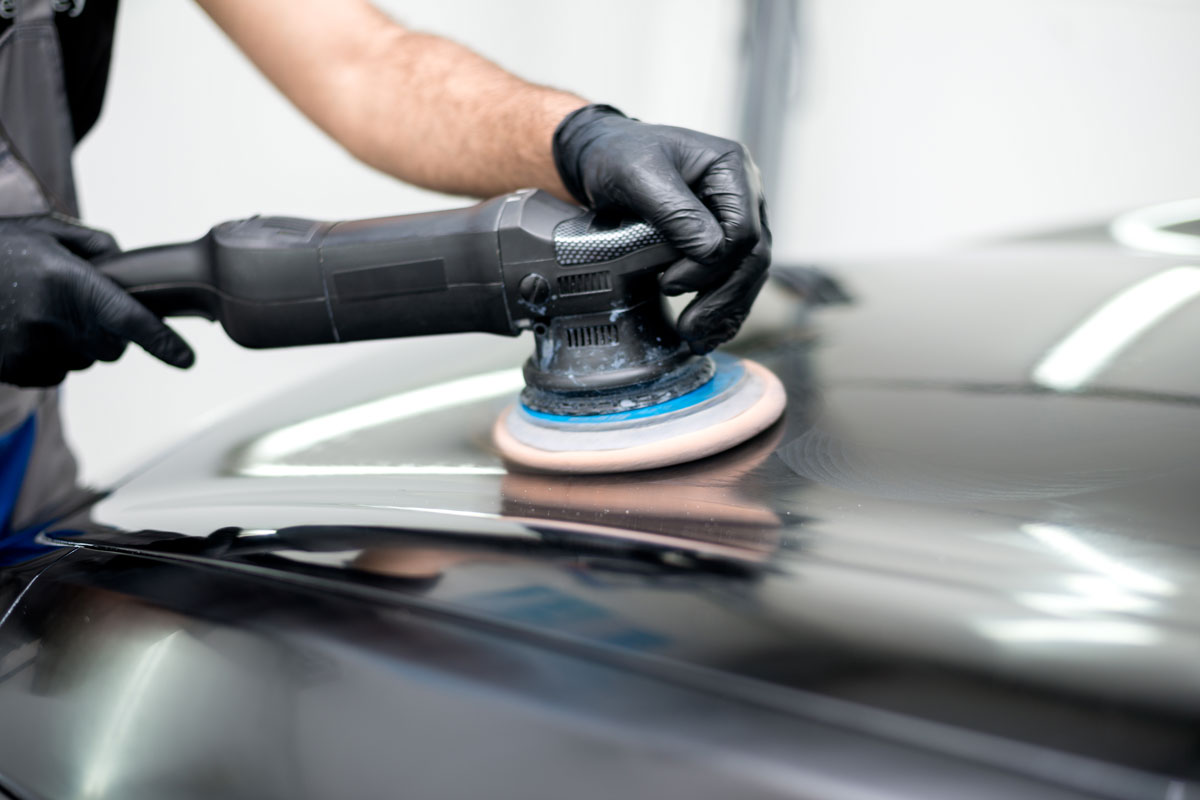 Car auto detailer polishing a car using an orbitall polisher