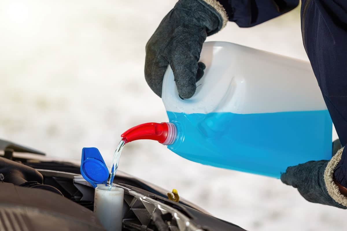 Car mechanic pouring new coolant to the reservior