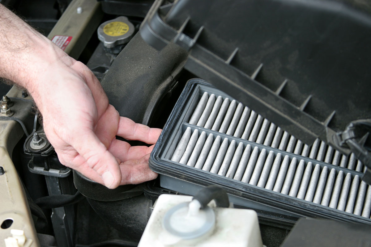 Car mechanic replacing a used air filter of a car