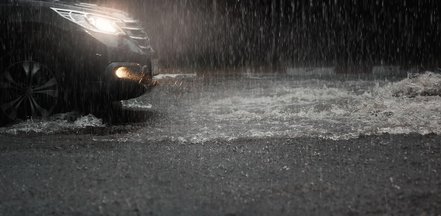 Car with headlights run through flood water after hard rain fall at night
