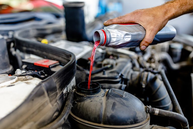 Close-up View of an Experienced Car Mechanic who is Pouring a Coolant in the Tank in Car - Can You Use RV Antifreeze In A Car