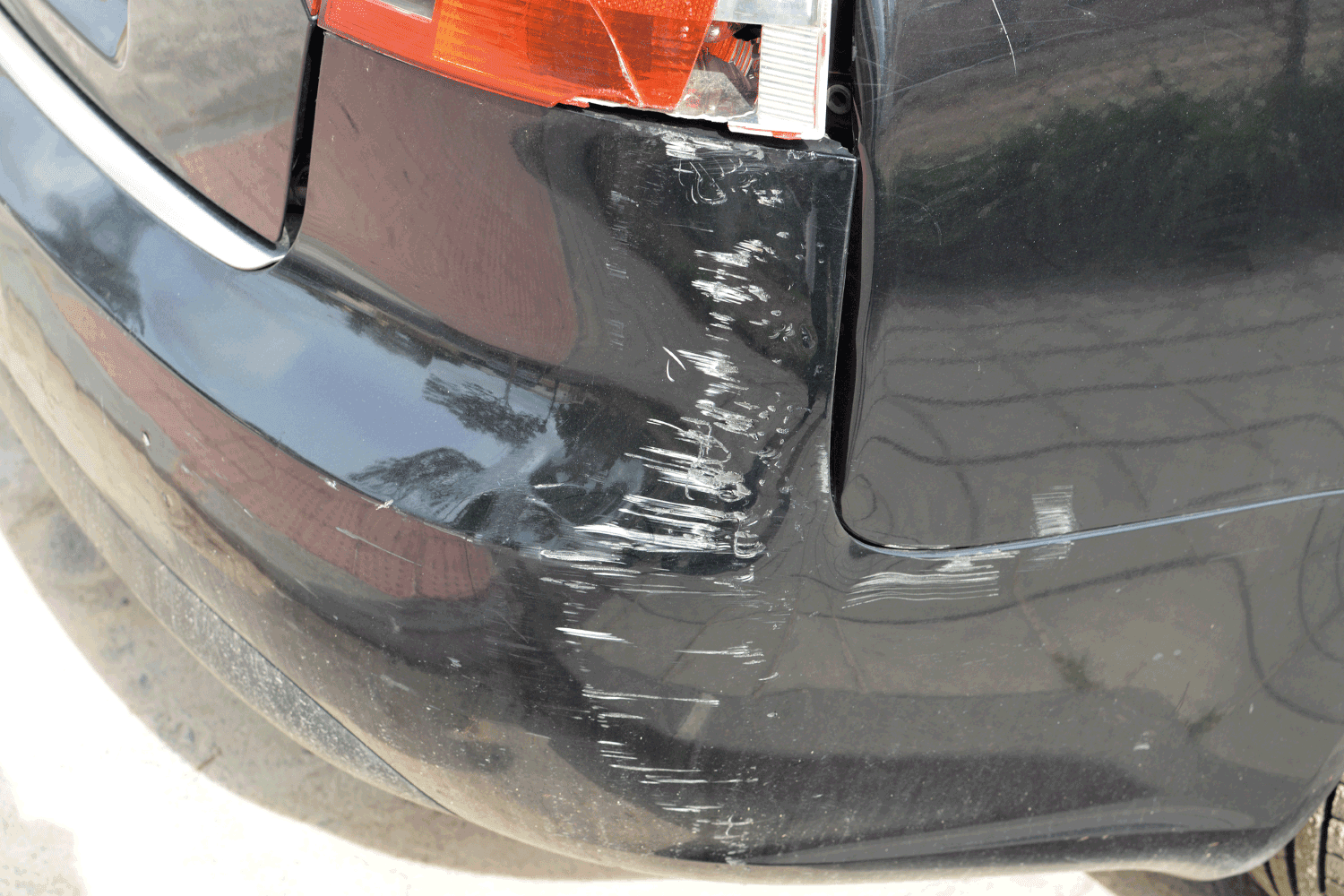 Close up of scratches and white scuff marks on rear end of black car