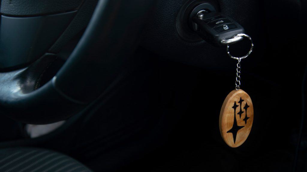 A wooden Subaru keychain hangs in the ignition. Selective focus.