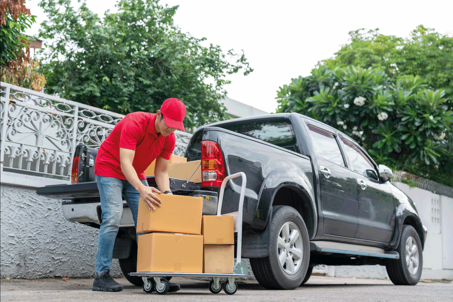 Delivery men in red uniform unloading cardboard boxes from pickup truck
