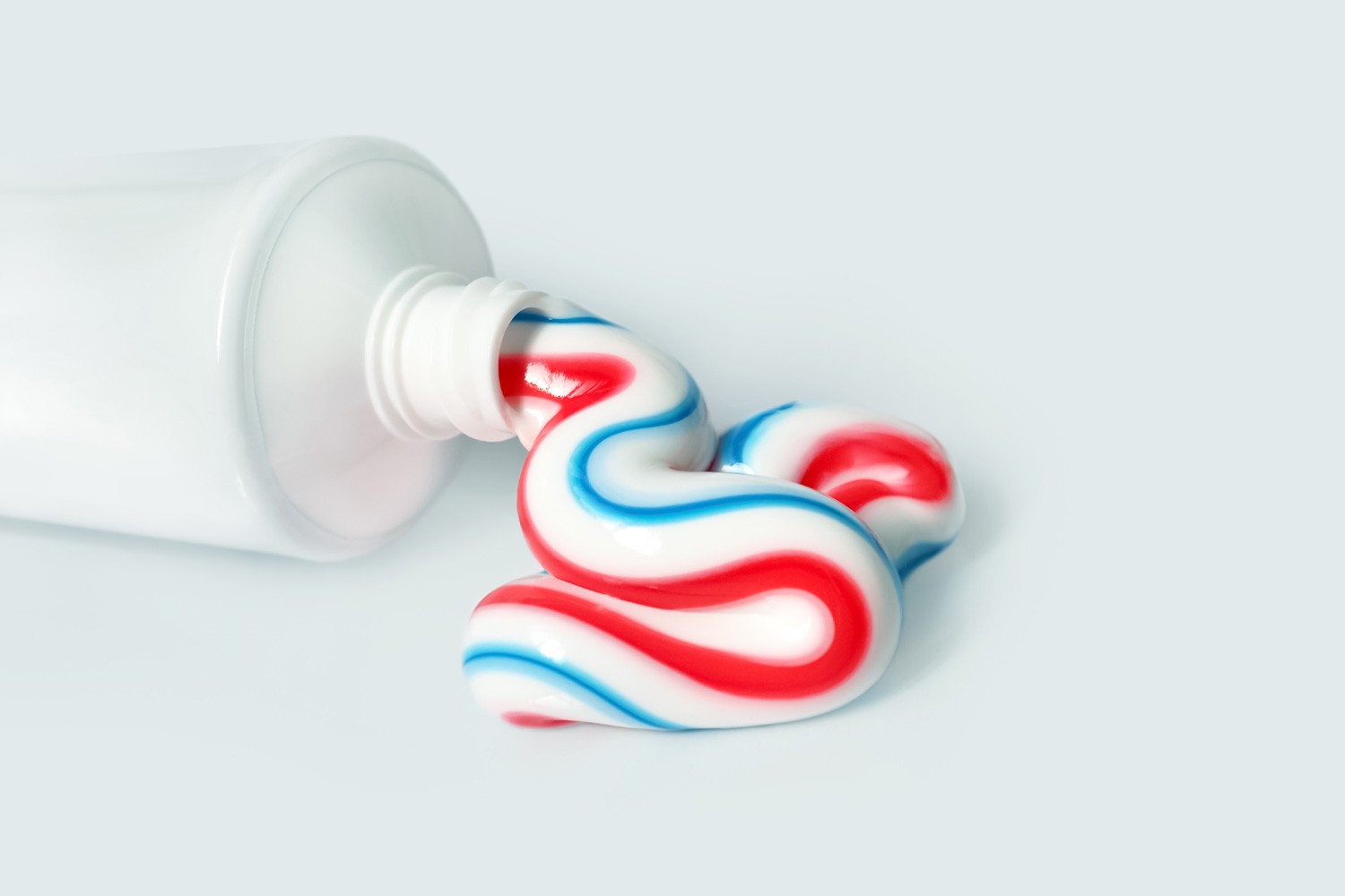 Dental hygiene product. Tricolor toothpaste. White tube with toothpaste isolated on light background