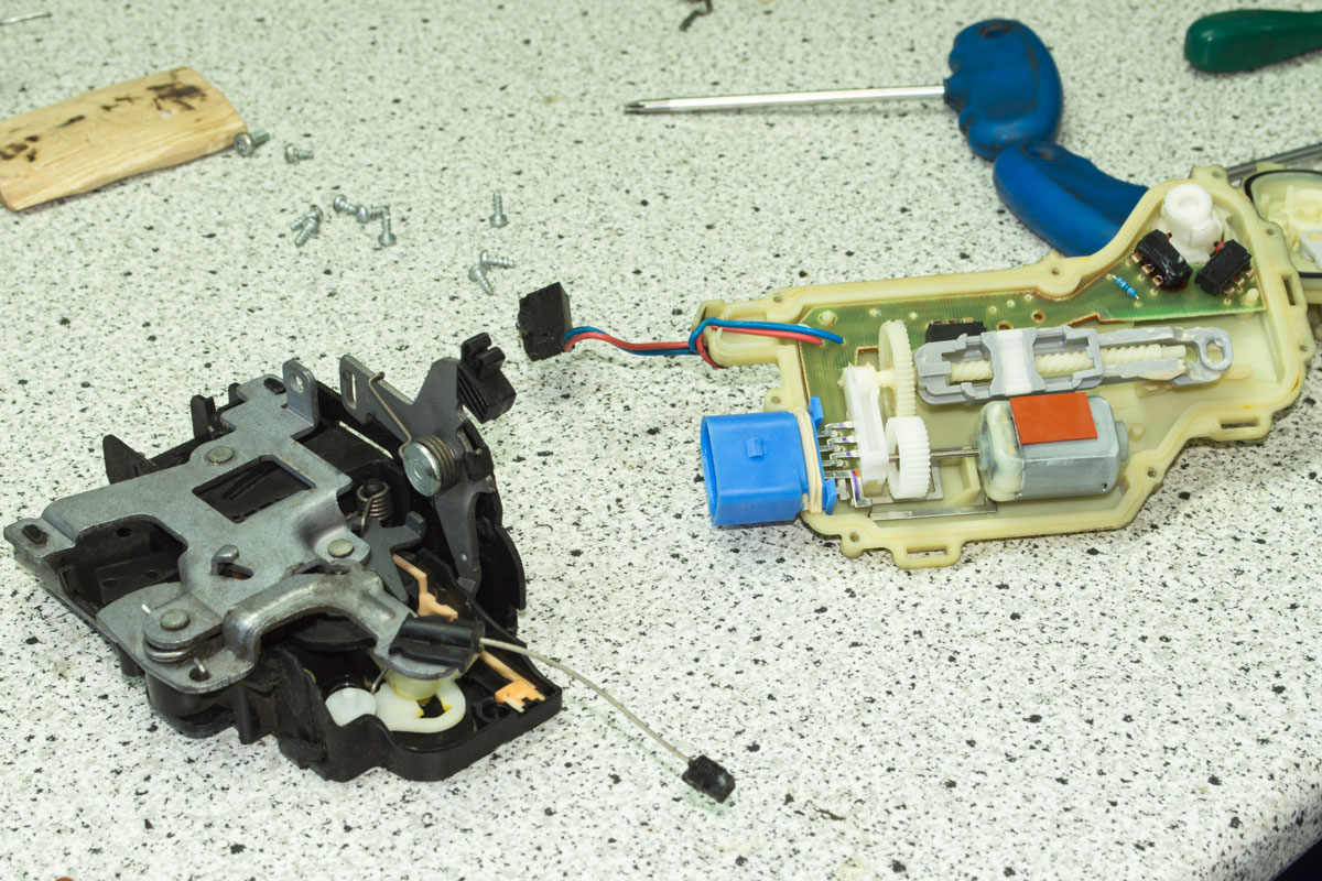 Disassembled electric car door lock is on the gray