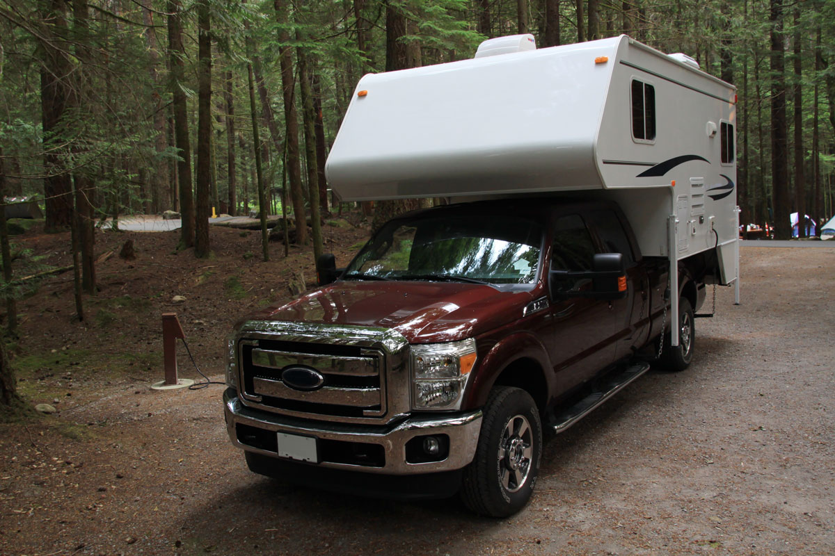 Ford F150 carrying a white truck camper