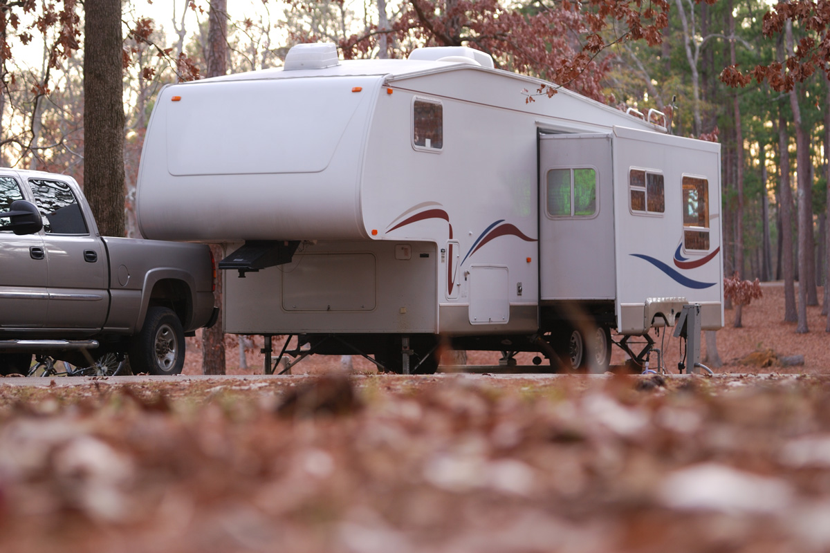 Ground view of a fifth wheel camper trailer in a wooded campsite