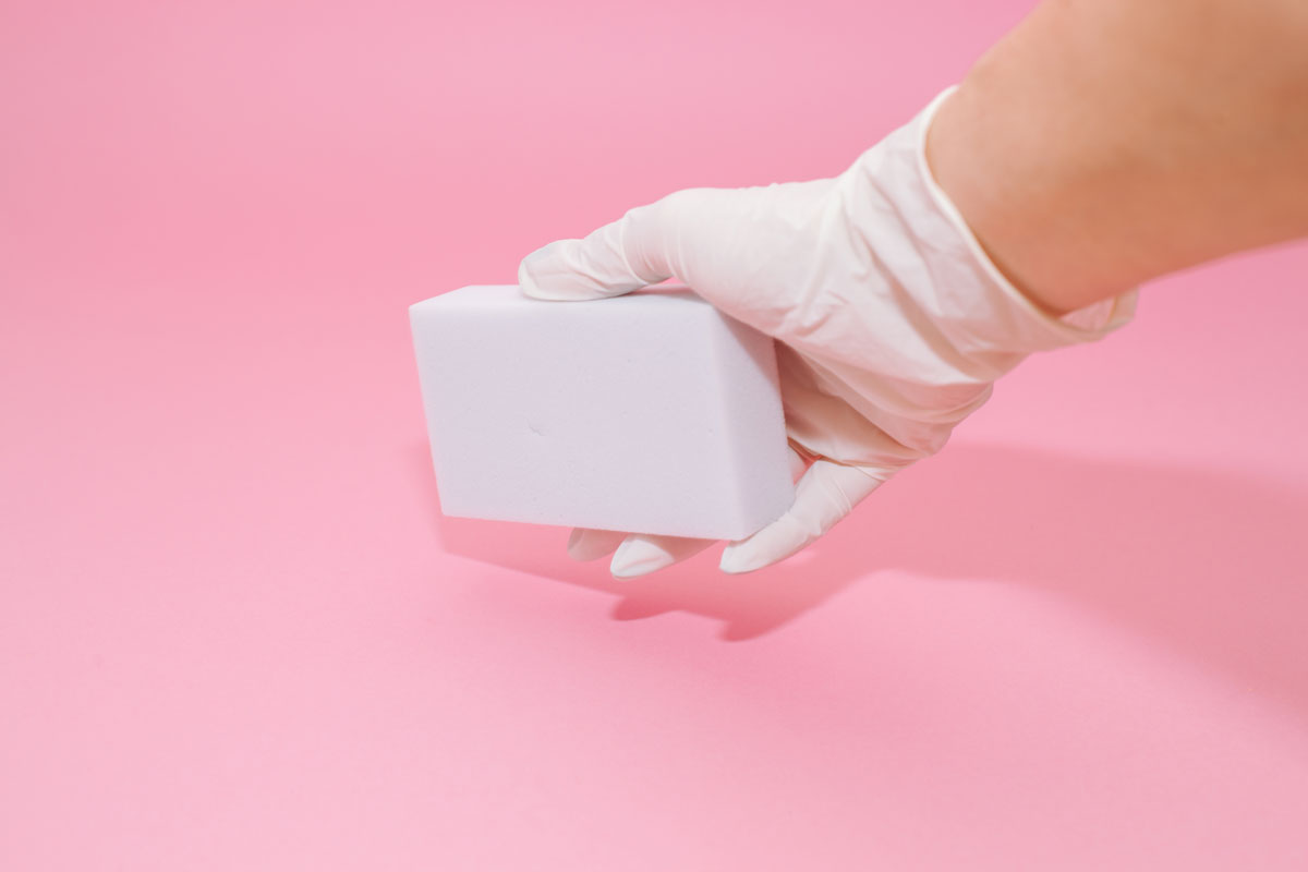Holding a white bar of magic eraser on a pink background