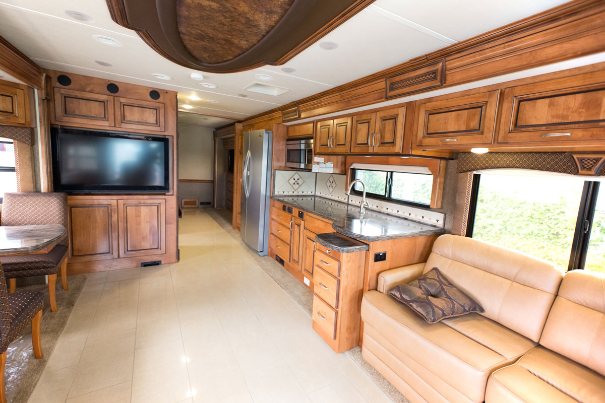 Interior of a luxurious modern RV with tiled flooring and oak cabinets and cupboards