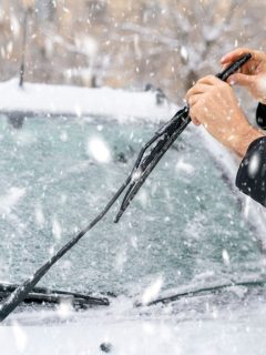 Man adjusting and cleaning wipers of car in snowy weather, Winter Wiper Blades Vs Regular: What's The Difference?