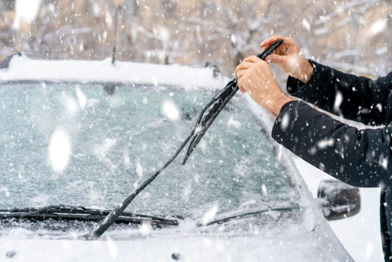 Man adjusting and cleaning wipers of car in snowy weather, Winter Wiper Blades Vs Regular: What's The Difference?