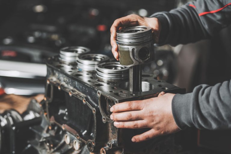 Mechanic placing a new piston to an engine block, Can A Seized Engine Be Fixed? [And Should It]