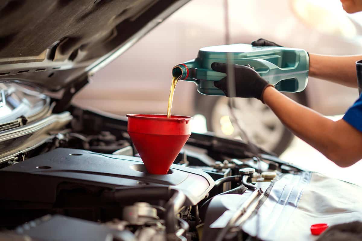 Mechanic pouring oil into car at the repair garage