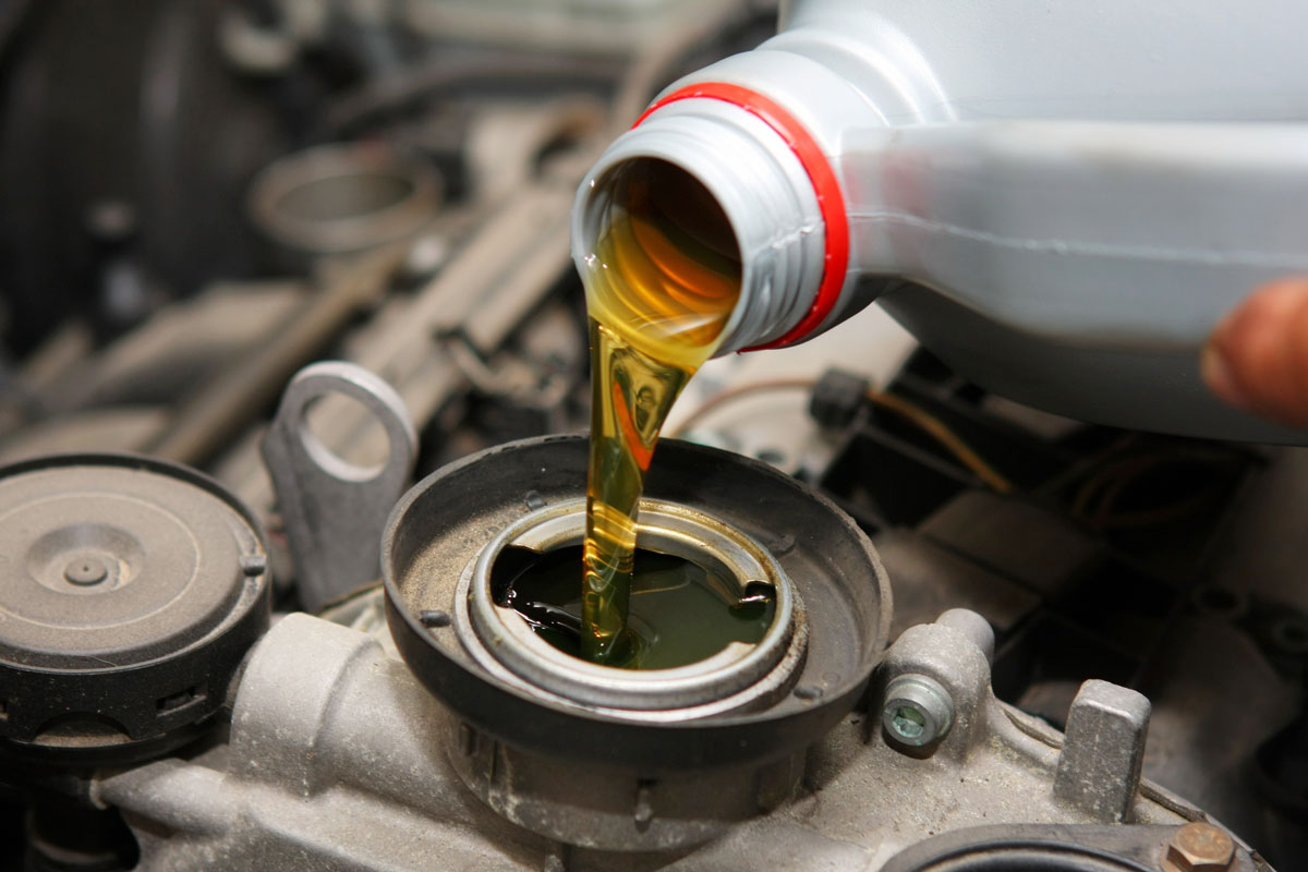 Mechanic pouring oil to the car engine