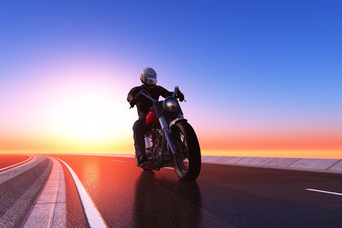 Motorcycle rider cruising with his bobber at sunset