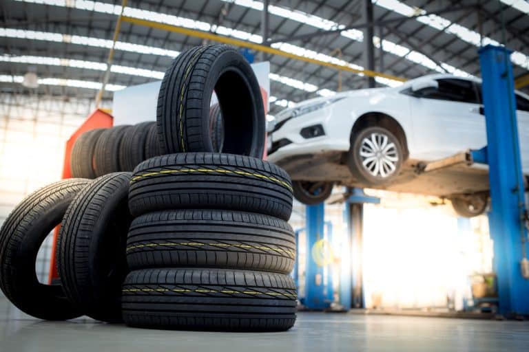 new tires that change tires in the auto repair service center, blurred background, the background is a new car in the stock blur for the industry, a four-wheeled tire set at a large warehouse - How Long Does It Take To Rotate Tires