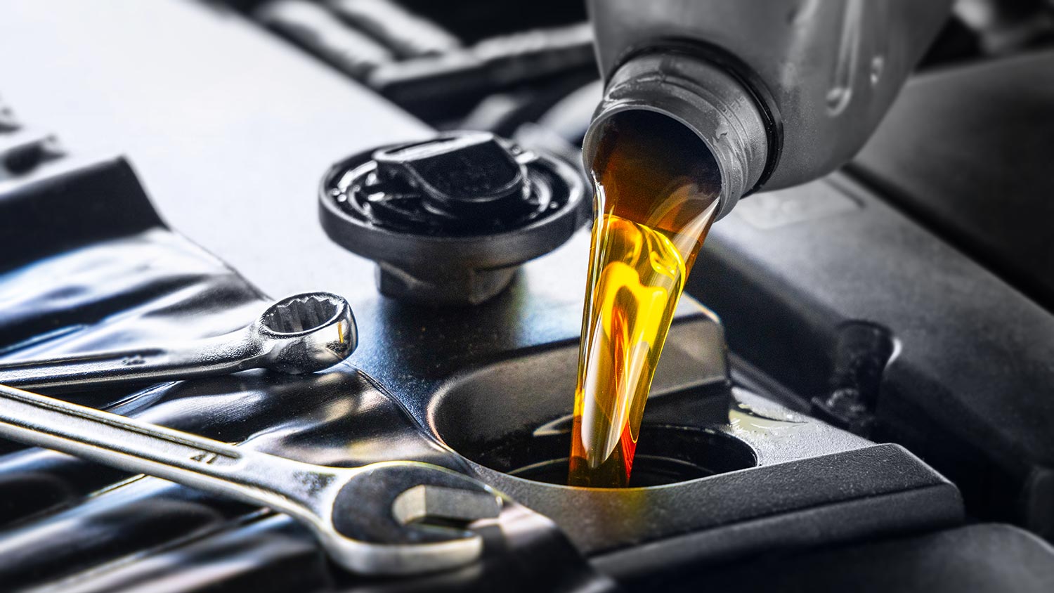 Pouring motor oil for motor vehicles from a gray bottle into the engine
