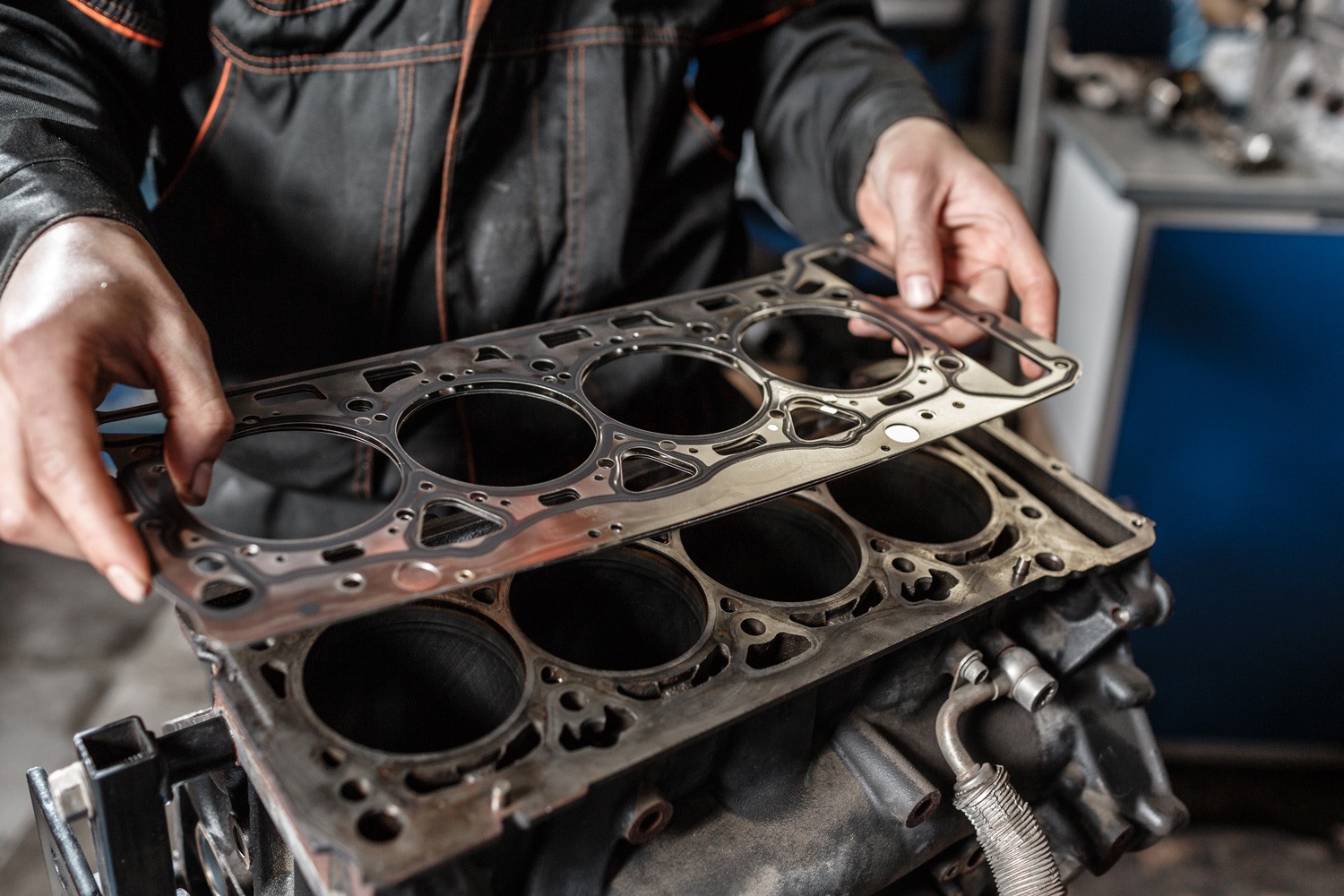 Sealing gasket in hand. The mechanic disassemble block engine vehicle. Engine on a repair stand with piston and connecting rod of automotive technology. Interior of a car repair shop.
