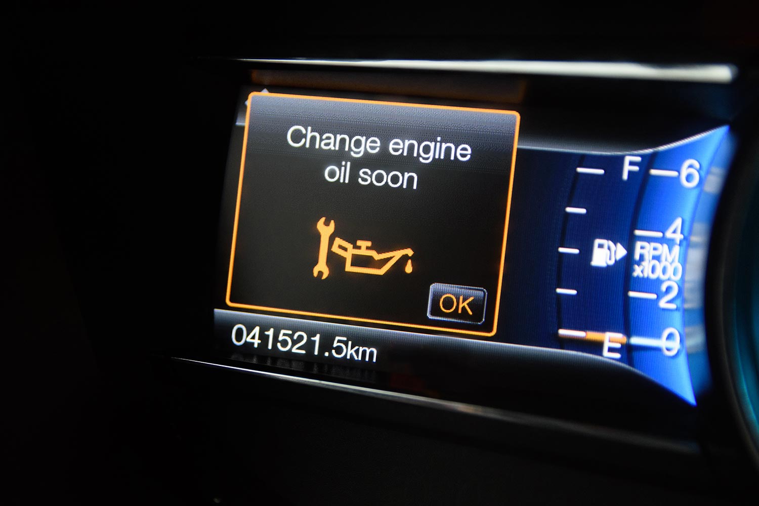 The modern car dashboard computer with color infographics warns the driver about changing engine oil soon