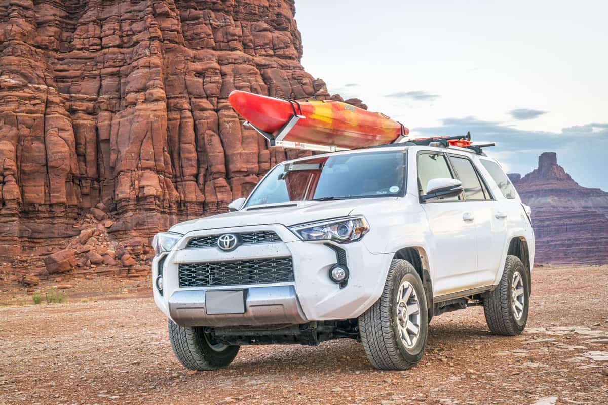 Toyota 4runner SUV (2016 trail edition) with a whitewater kayak on roof racks on a desert trail in the Moab area
