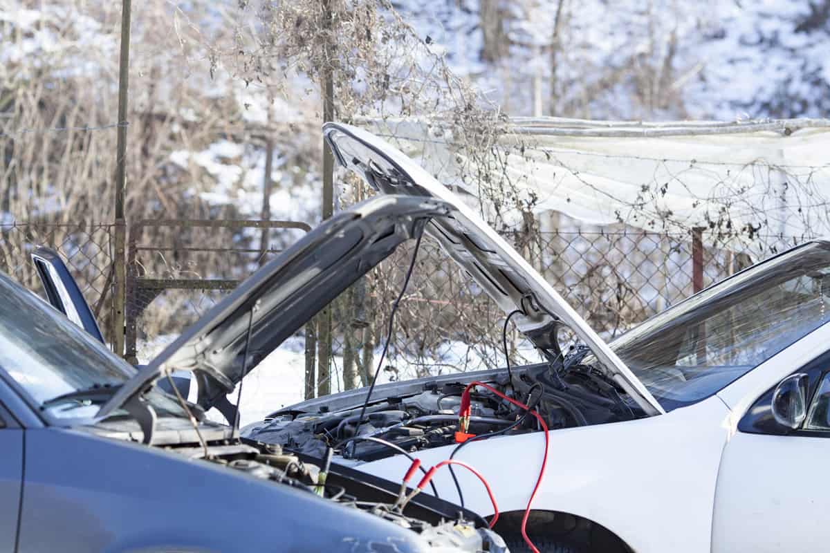 Two Parked Cars Sharing Battery Charge via Jumper Cables in Cold Weather.