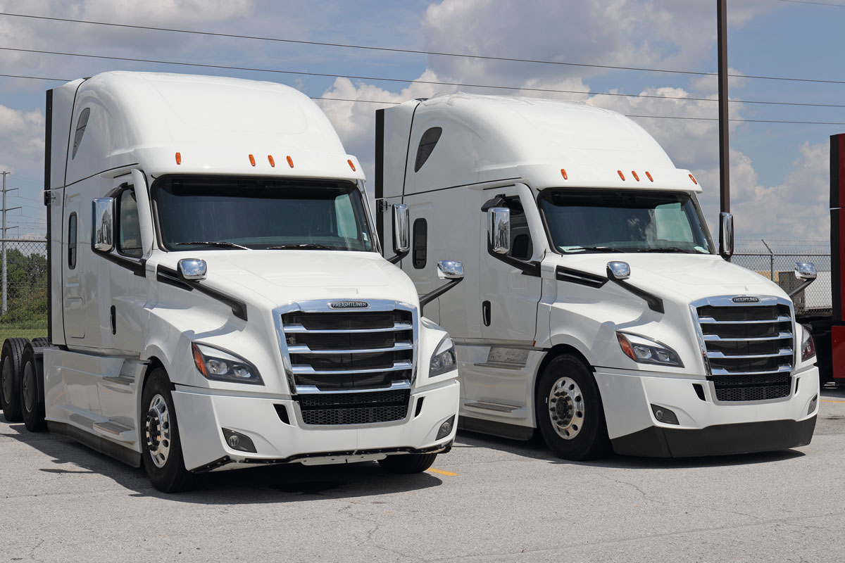 Two freightliner trucks parked at a dealership