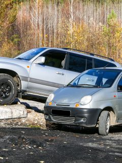Urban minicar Daewoo Matiz and offroad SUV Toyota Land Cruiser 100 near an abandoned building, How Many Gallons Does A Typical Car Hold?