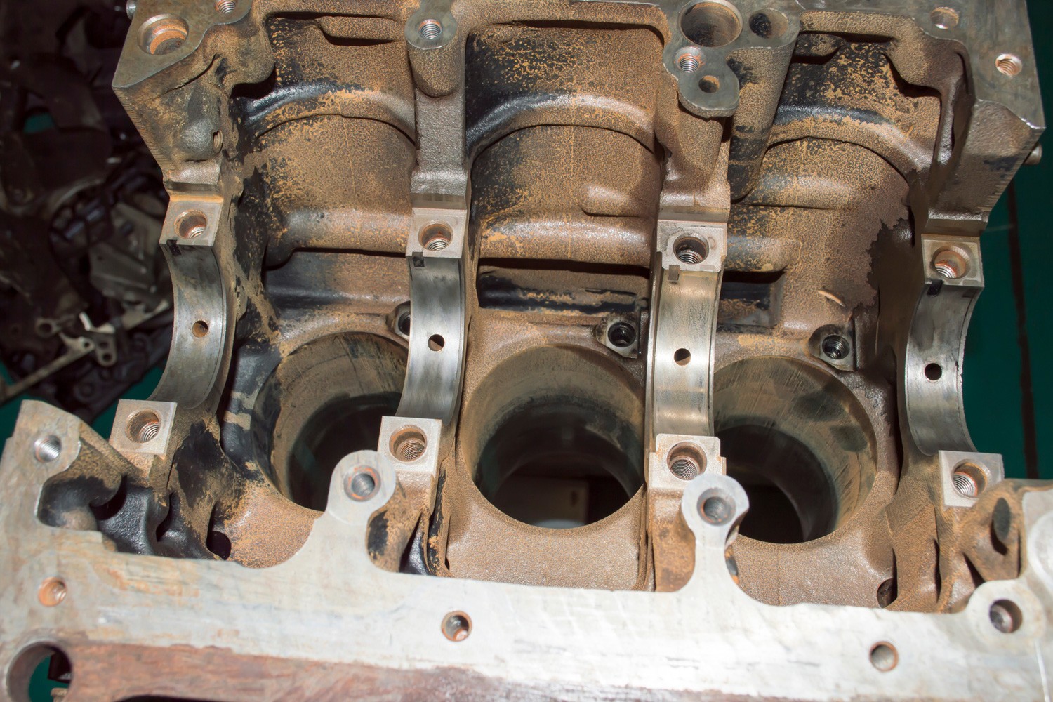 View of an old rusty three-cylinder cylinder block of an automobile internal combustion engine from the installation site of the crankshaft