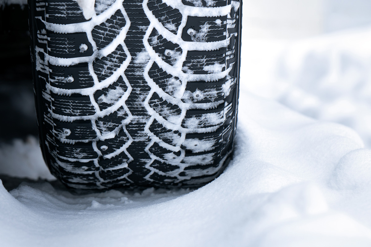 Winter studded tire tread standing in the snowdrift close up after a hard snow storm in winter
