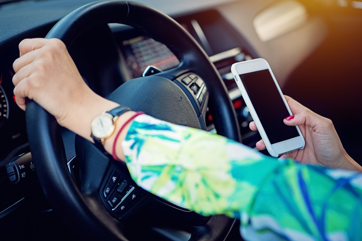 Woman is using connecting mobile phone to her car