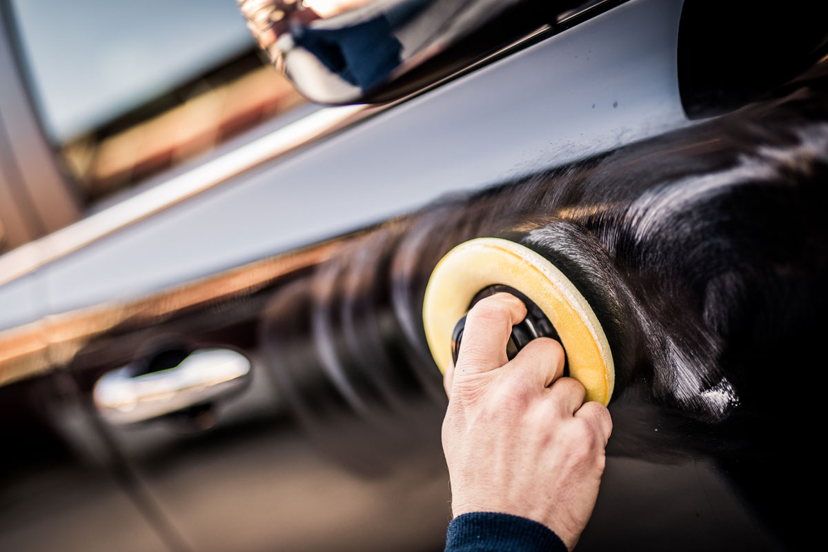 Worker polishing a car with a small applicator pad