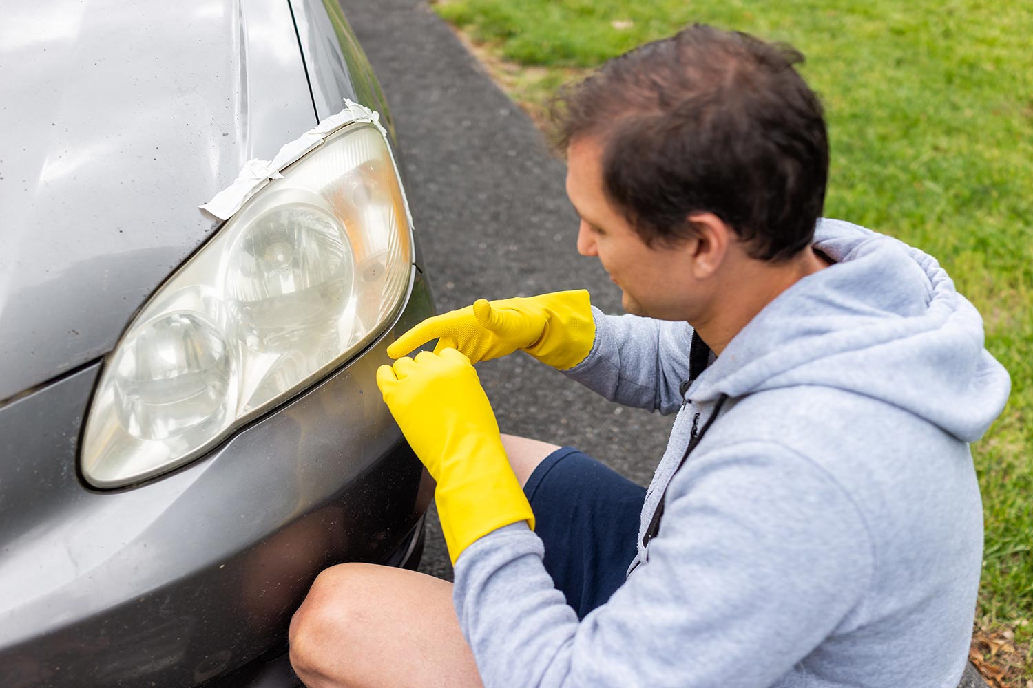 Worker putting gloves on for cleaning car dirty foggy headlights