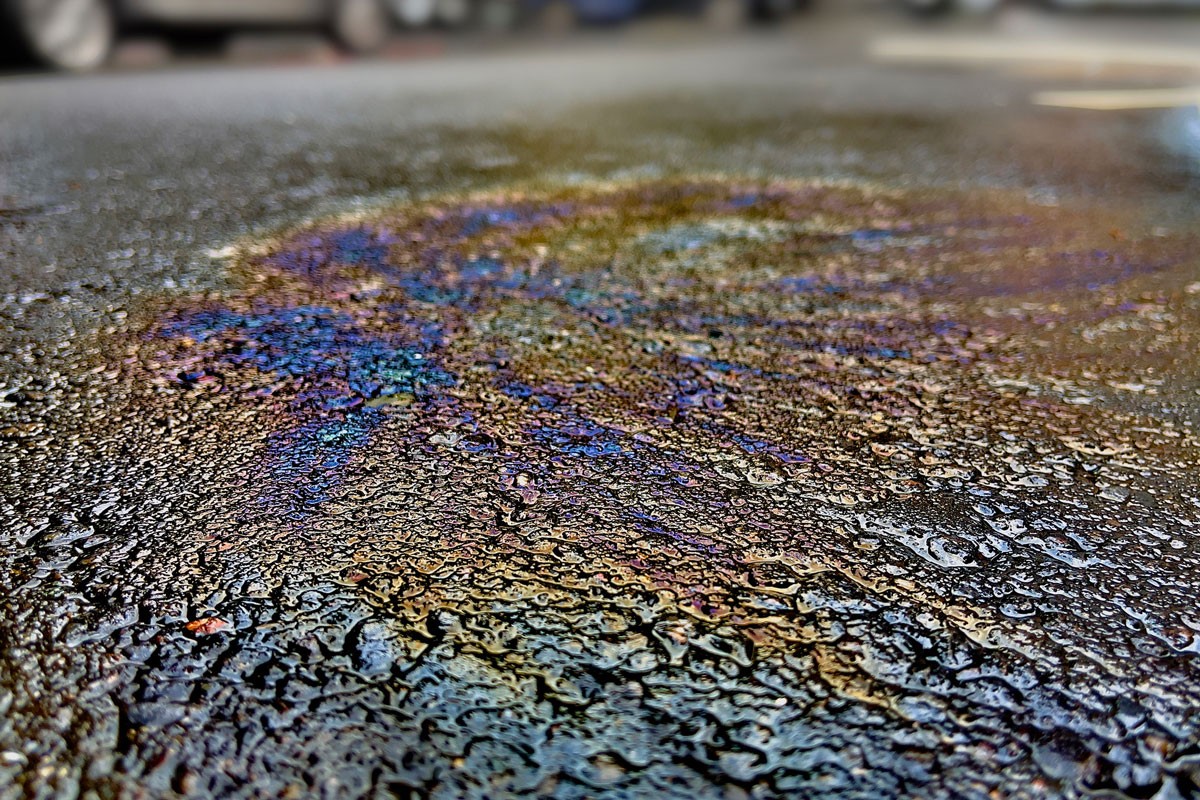oil spill on asphalt road with rainbow reflection on it