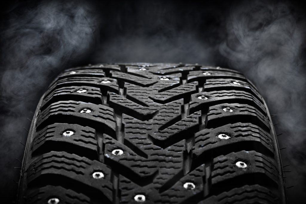 winter studded tyre dark moody. steam on background. studio shot